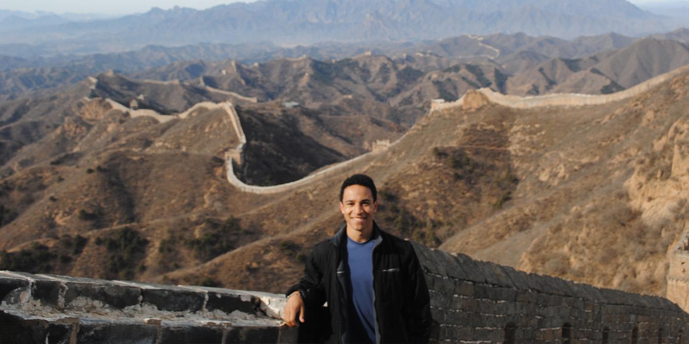 Ricky Bailey stands and smiles at the Great Wall of China