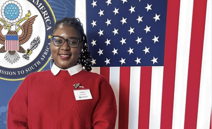 Dr. Thabang Msimango poses in front of an American flag. 