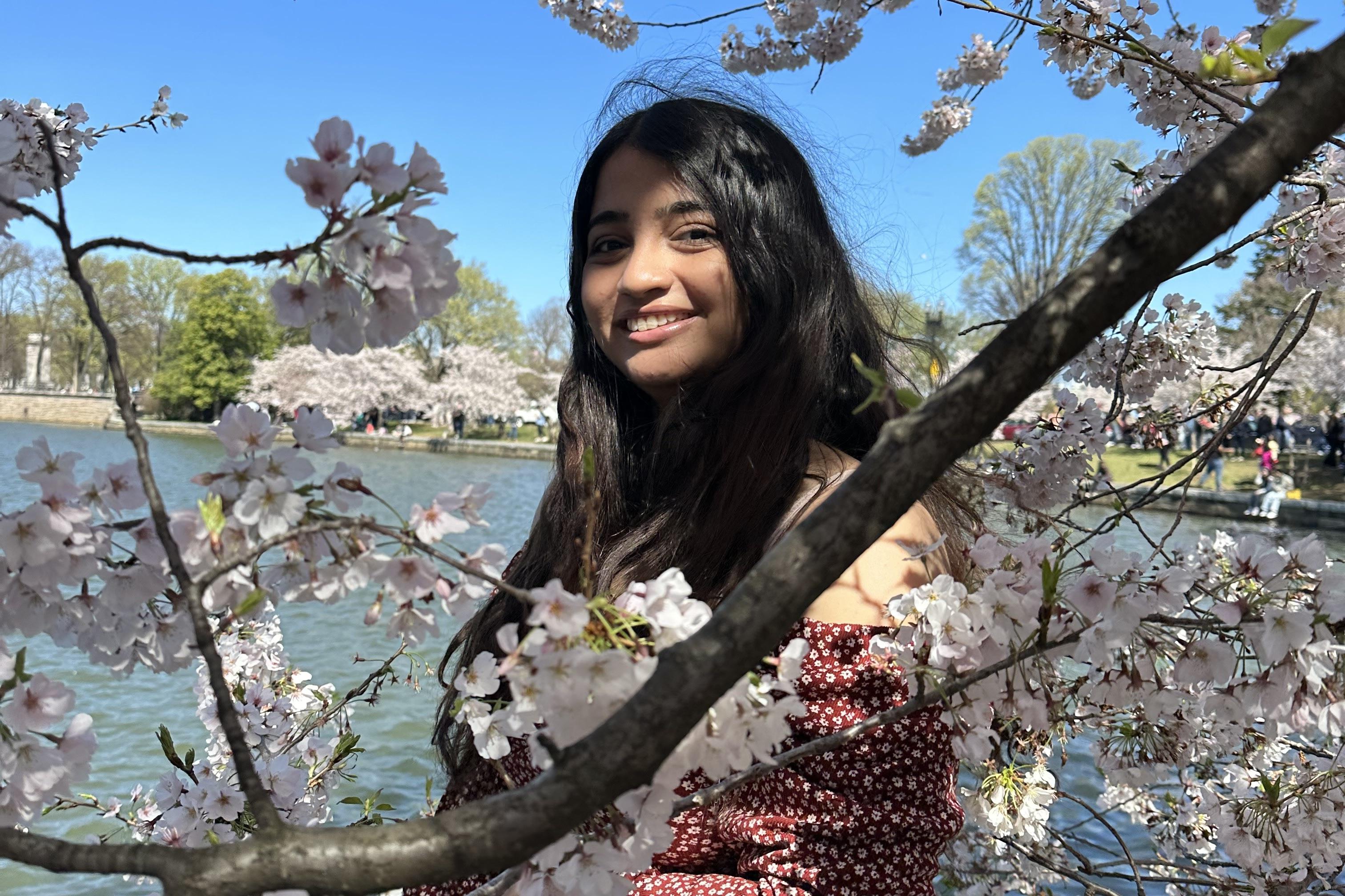 Sadaf stands in front of a cherry blossom branch at the D.C. Tidal Basin.